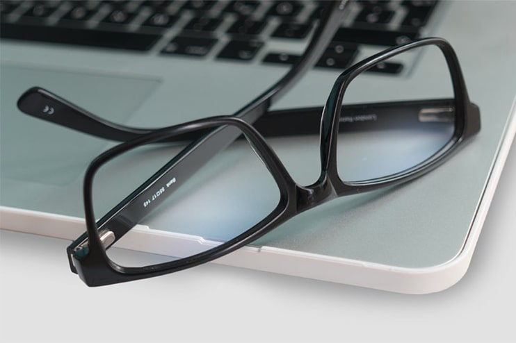 A pair of glasses lying on a laptop
