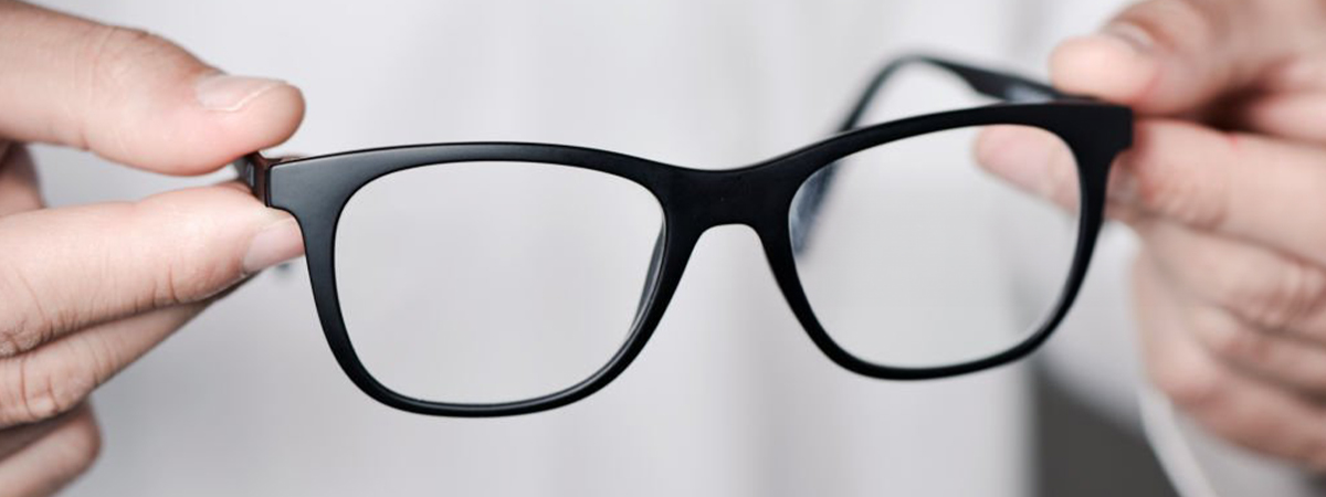 Close-up of a pair of glasses being held up carefully by their arms