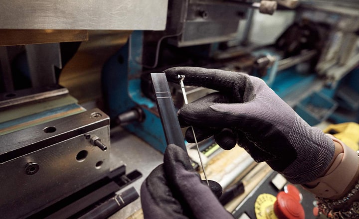 A pair of gloved hands working on some glasses parts next to heavy machinery