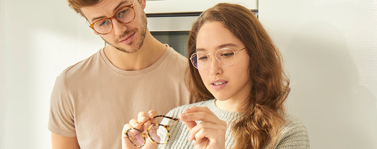 A young man and woman looking at a pair of glasses in their home