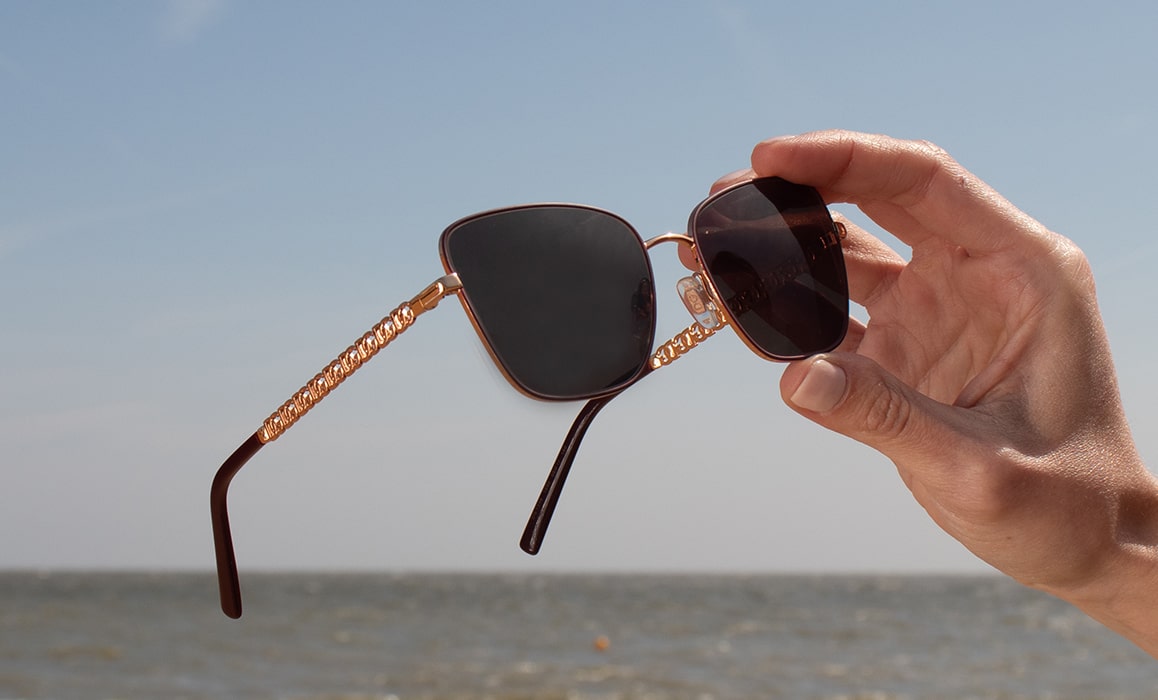 A pair of sunglasses being held up to the sun