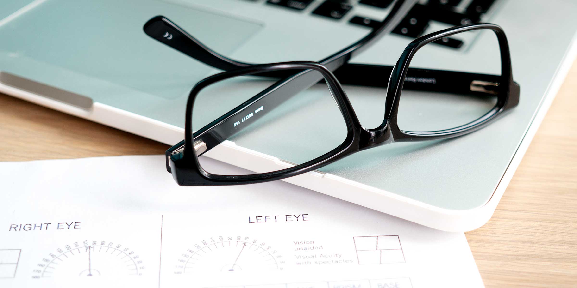 A black glasses frame lying on a laptop