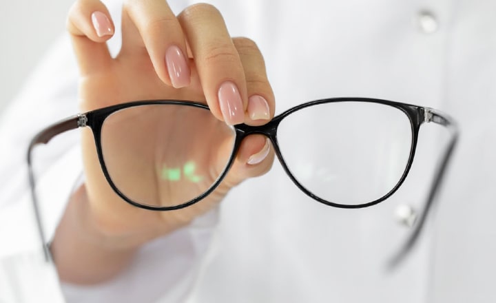 Close-up of a pair of glasses being held up by a woman's hand