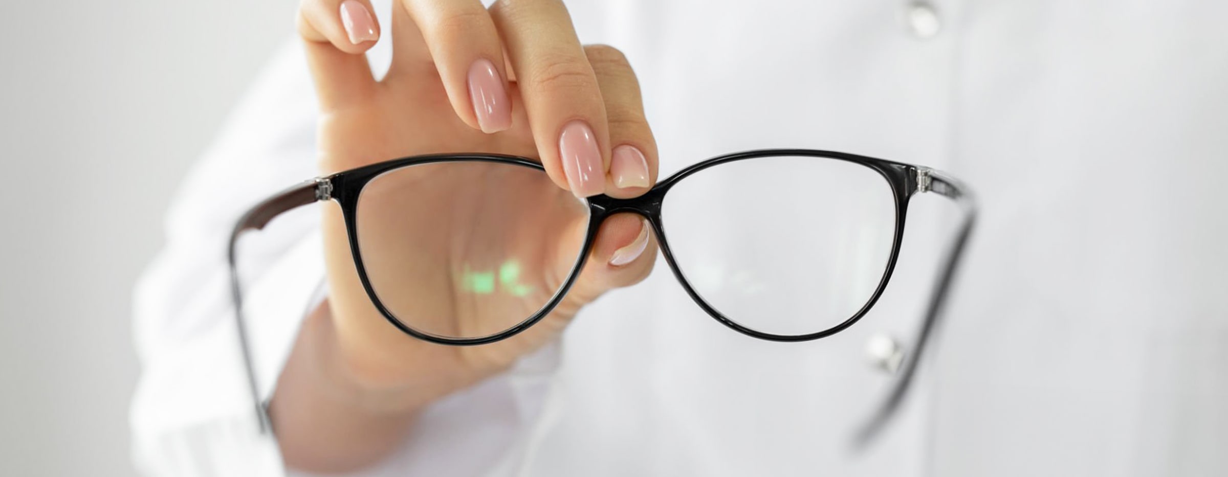 Close-up of a pair of glasses being held up by a woman's hand