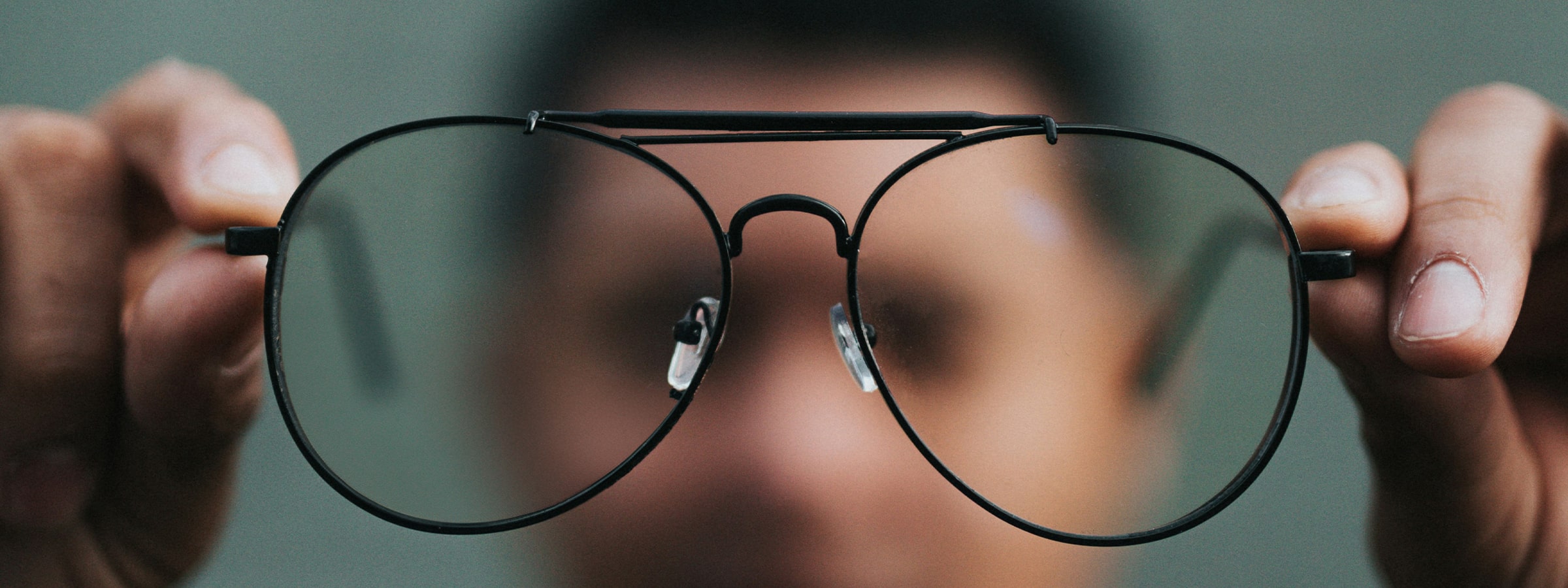 Blurry image of a man holding up a pair of glasses