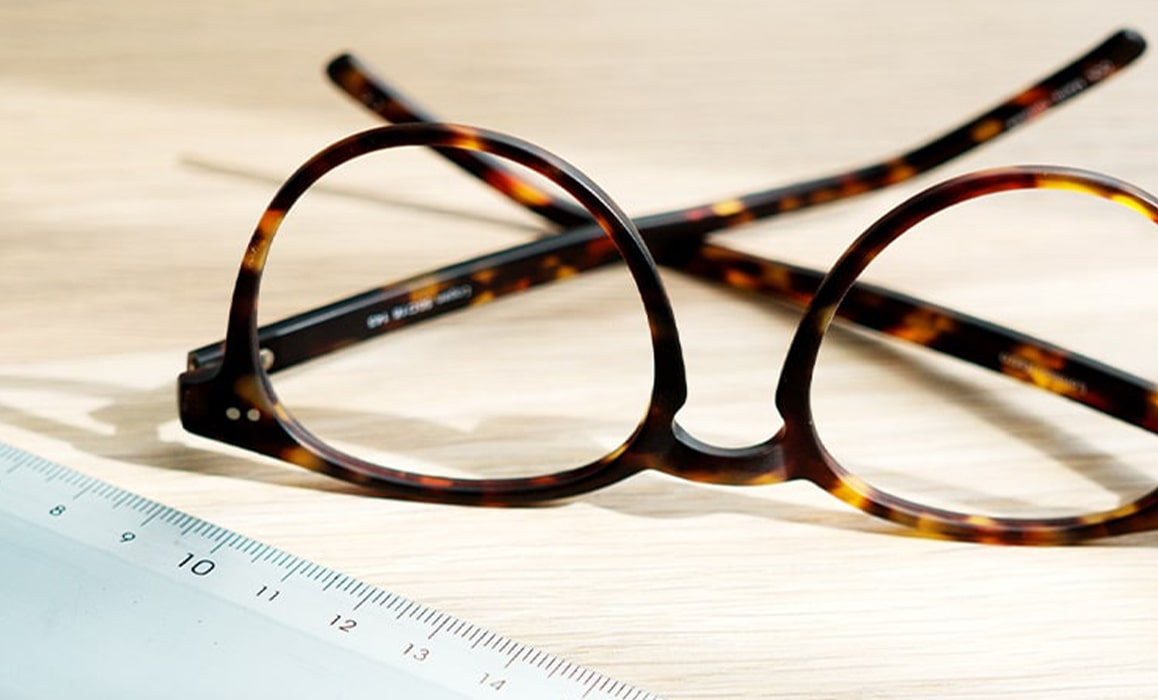 A pair of glasses next to a ruler