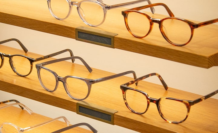 Glasses frames laid out on wooden shelves in a store