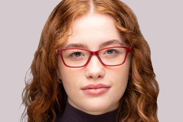 Woman with wavy red hair wearing red rectangular glasses frames