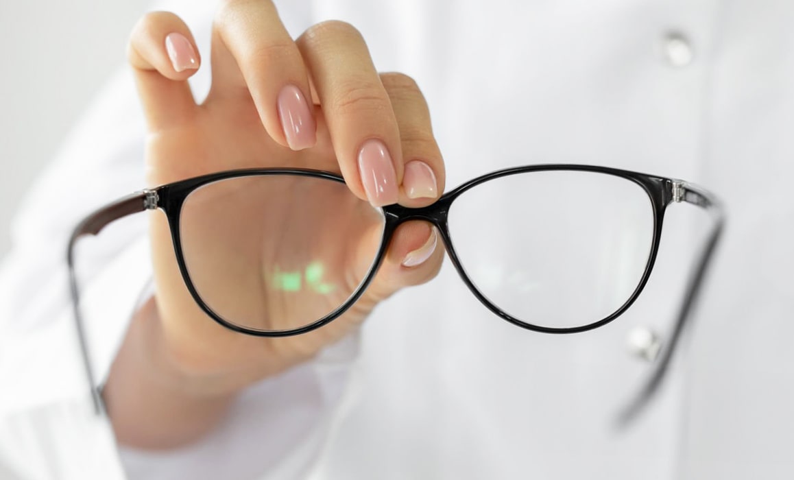 Close-up of a pair of glasses being held up by a woman's hand