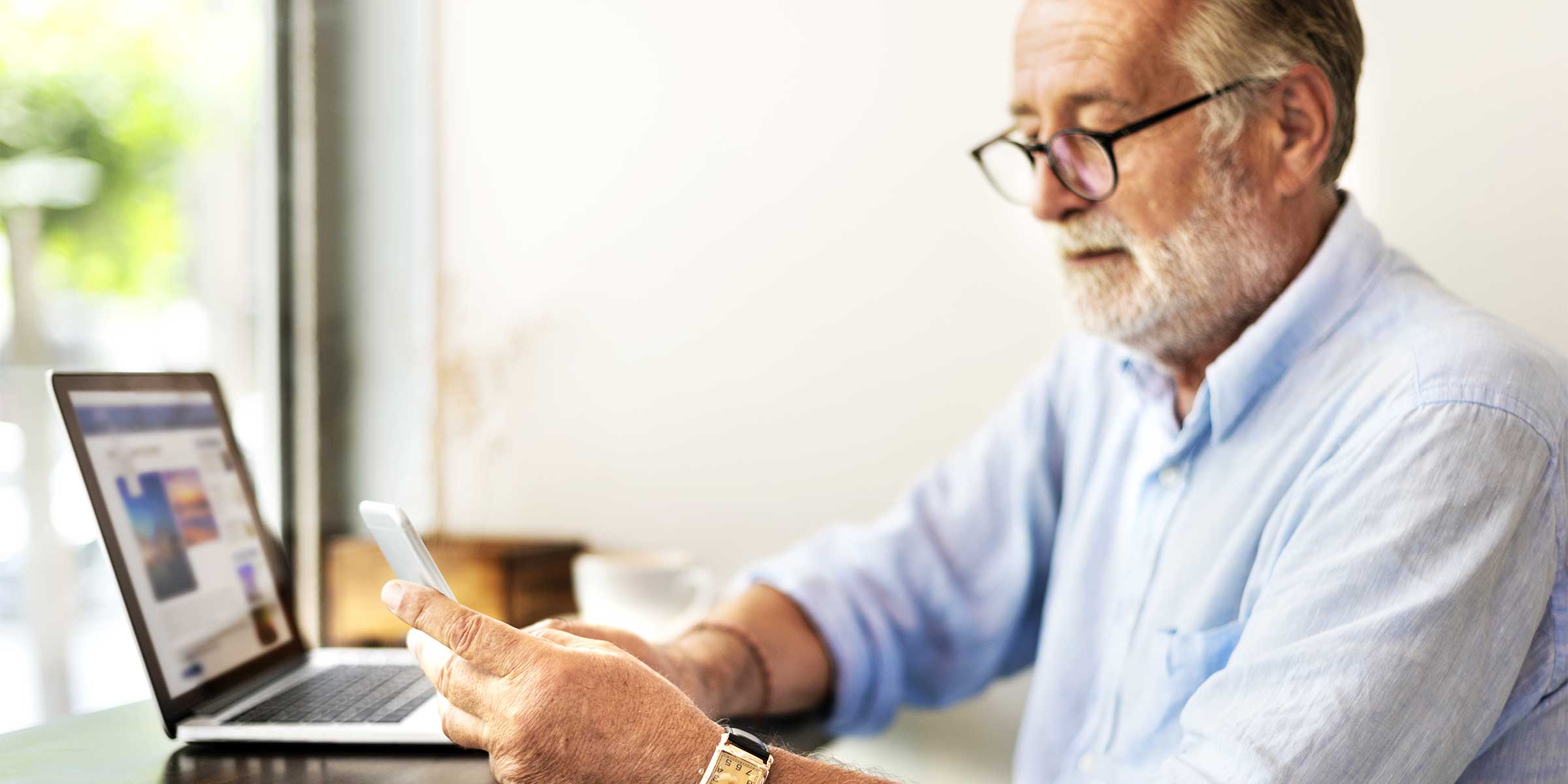 An older man looking at his phone through glasses