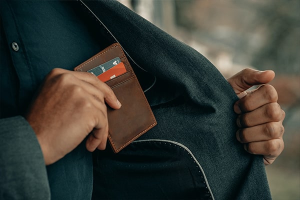 A man putting his wallet back into his coat pocket