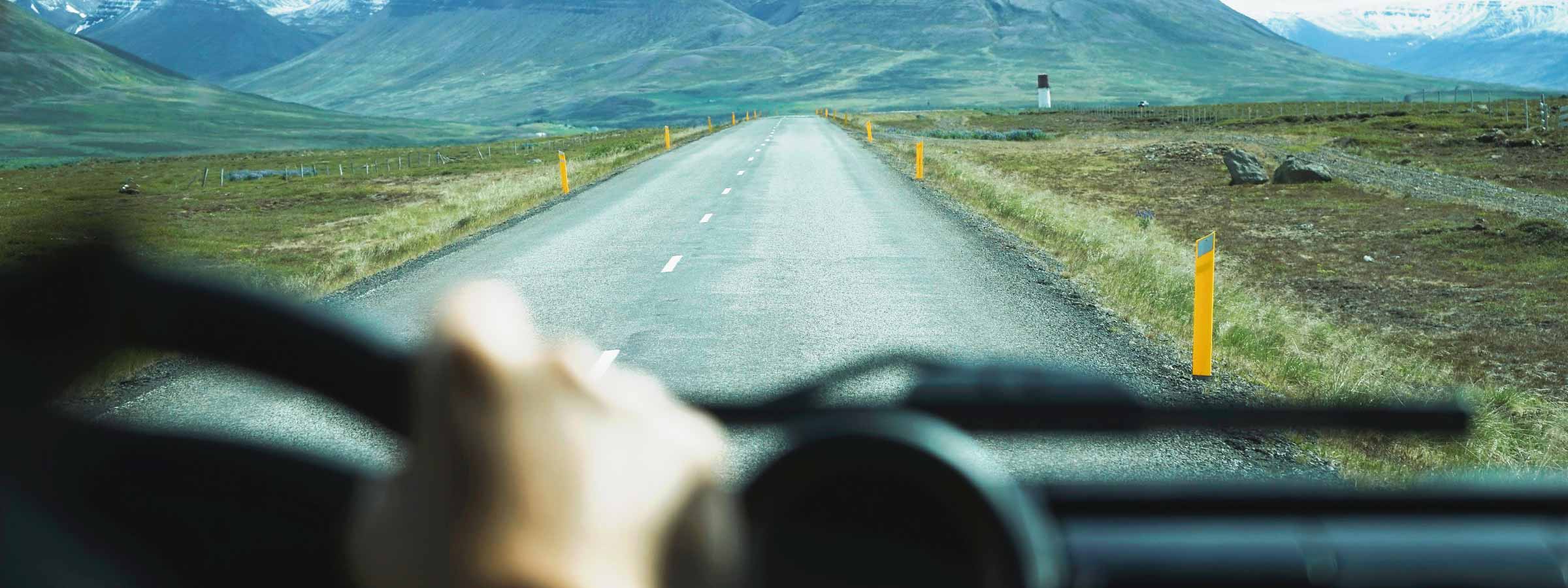 A country road as seen from inside a car with a blurry interior