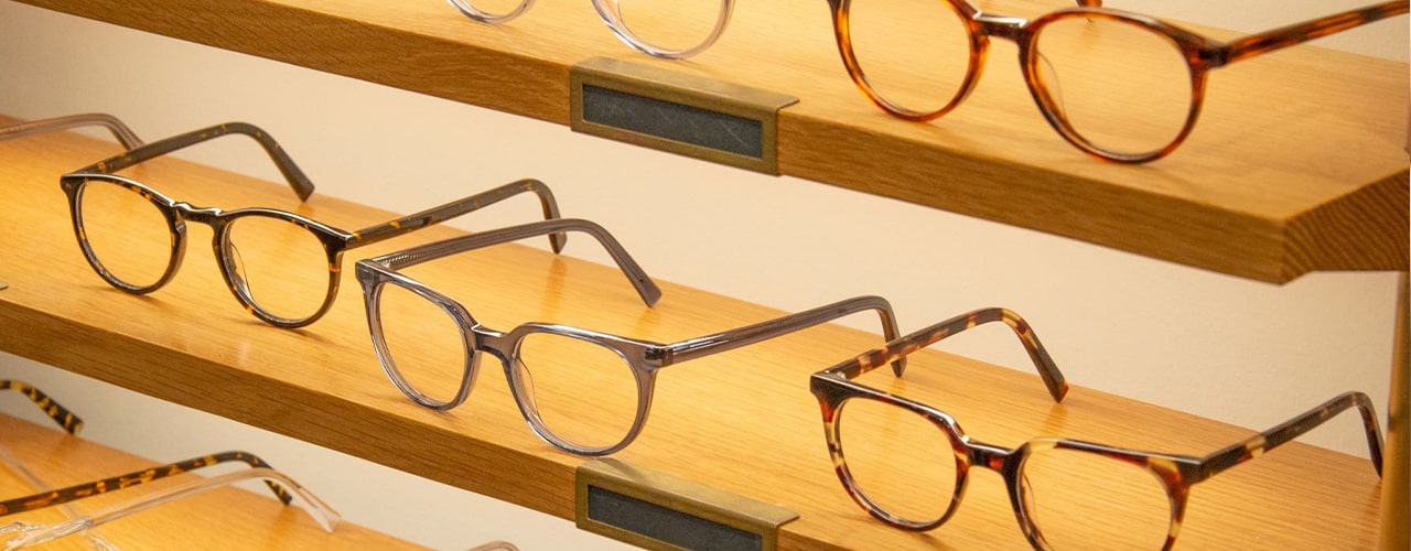 Glasses frames laid out on wooden shelves in a store