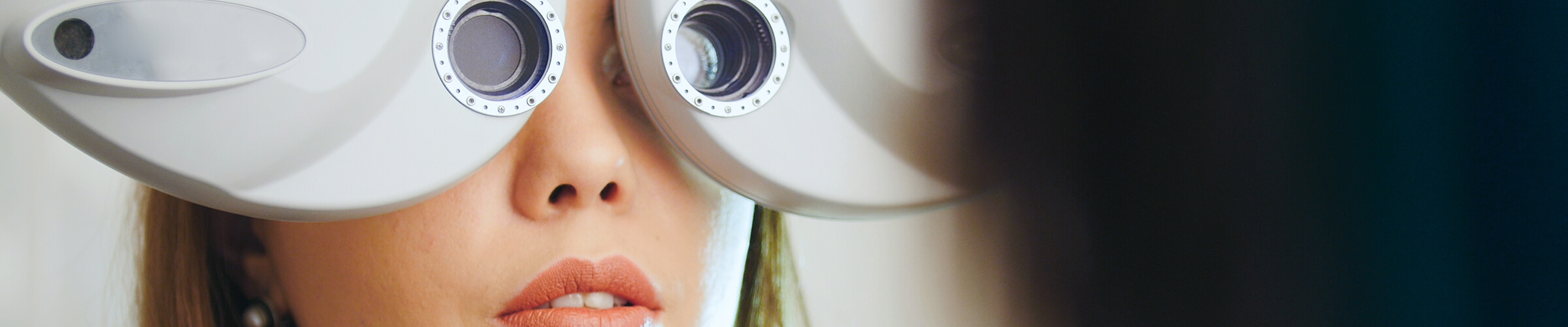 Close-up of a woman looking through a phoropter