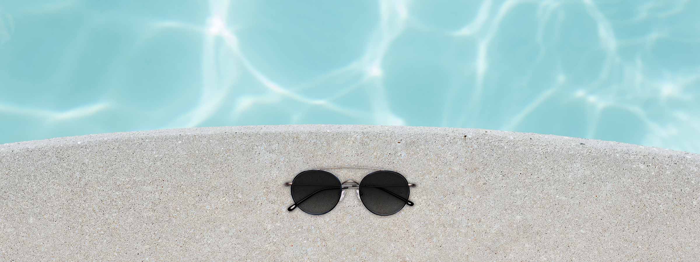 A pair of sunglasses by the side of a swimming pool