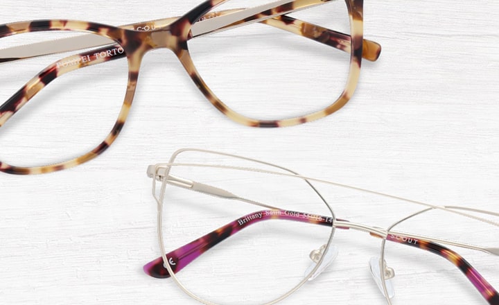 A tortoiseshell cat-eye frame and and an angular silver glasses frame with purple temple tips lying next to each other
