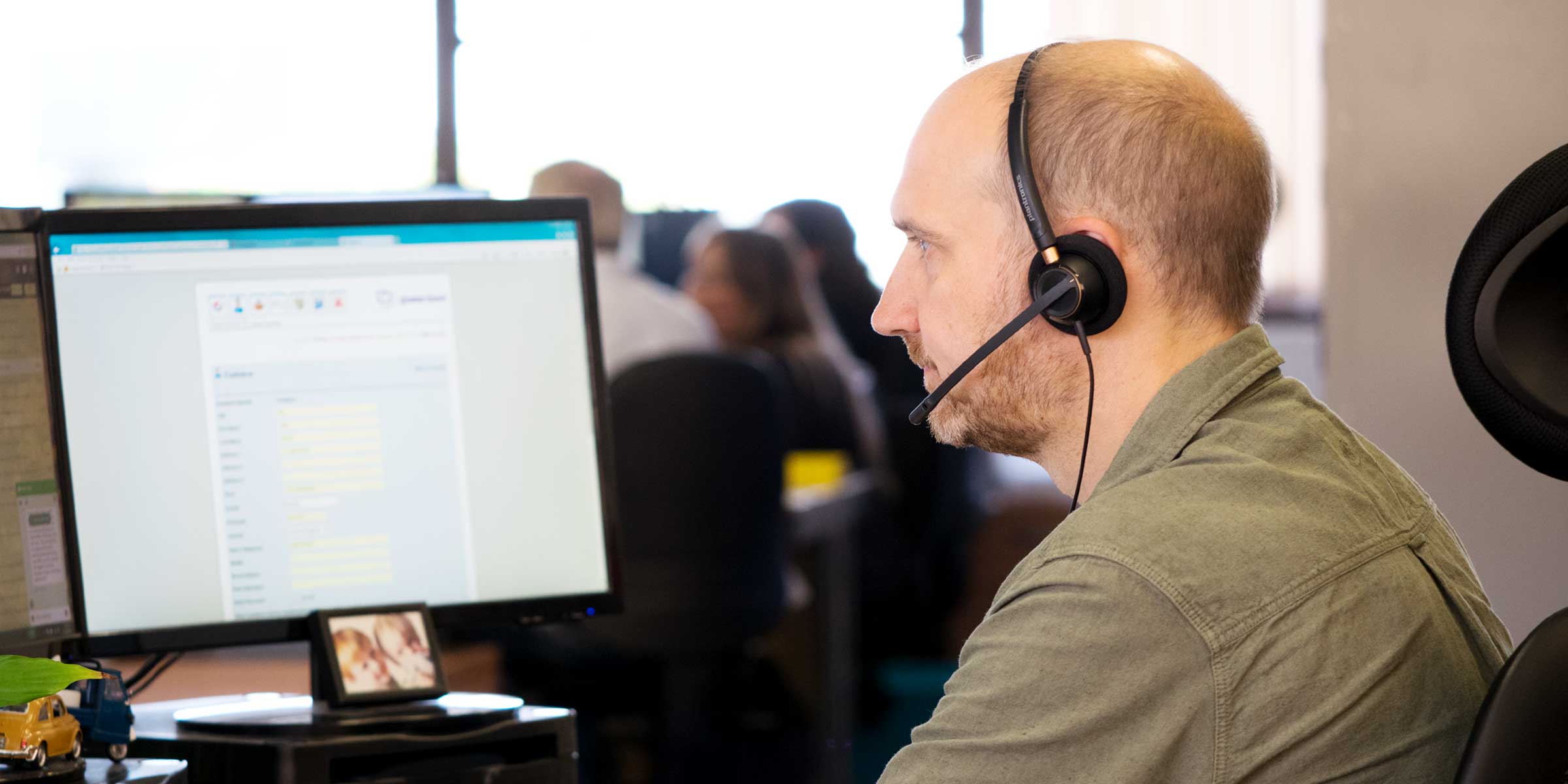 A customer service agent with a headset on and at his computer