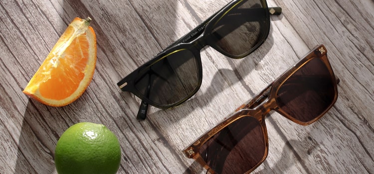 2 pairs of sunglasses next to citrus fruit