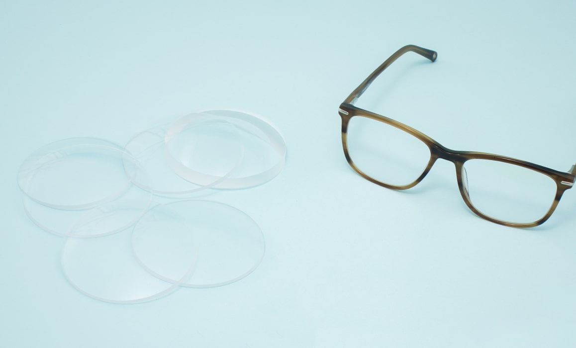A pair of glasses and several lenses lying on a table