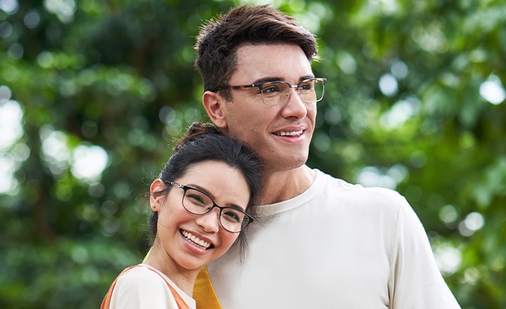 Happy woman and man wearing glasses outdoors smiling