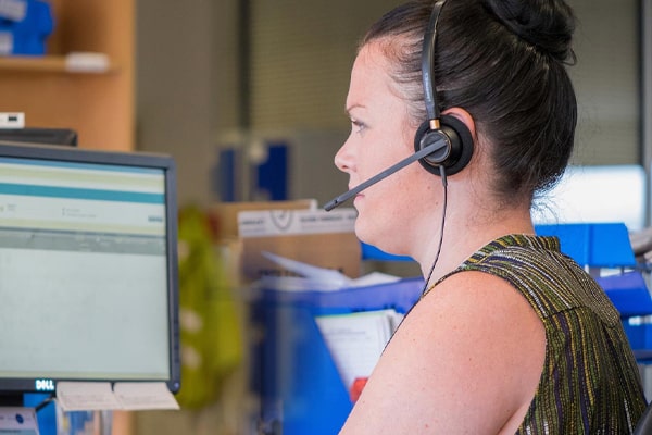 A female customer service agent wearing her headset, sitting at her PC