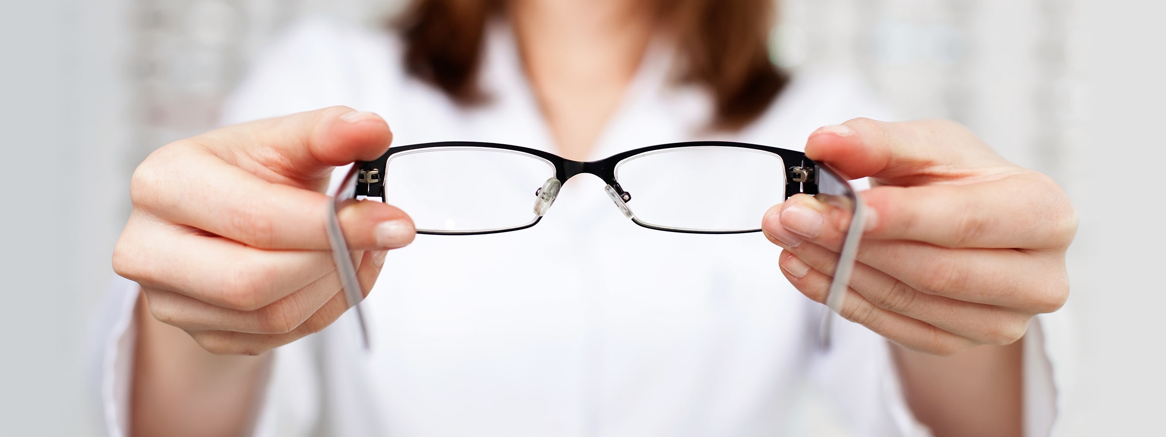 A woman holding up a pair of glasses