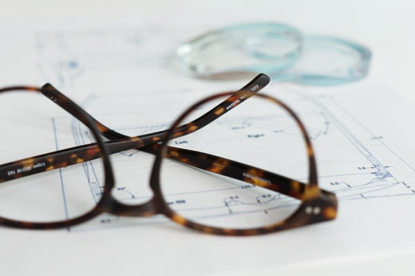 A frame and several lenses lying on top of a diagram that shows how to assemble a pair of glasses