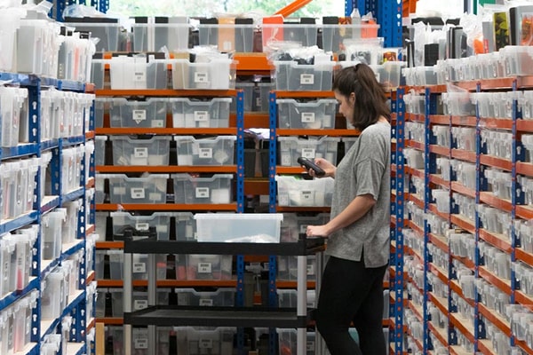 A woman scanning items while surrounded by bins in our warehouse