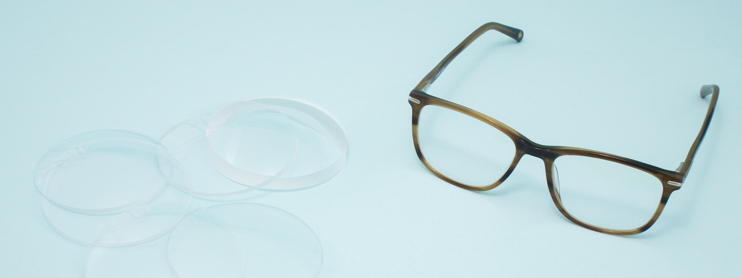 A pair of glasses and several lenses lying on a table