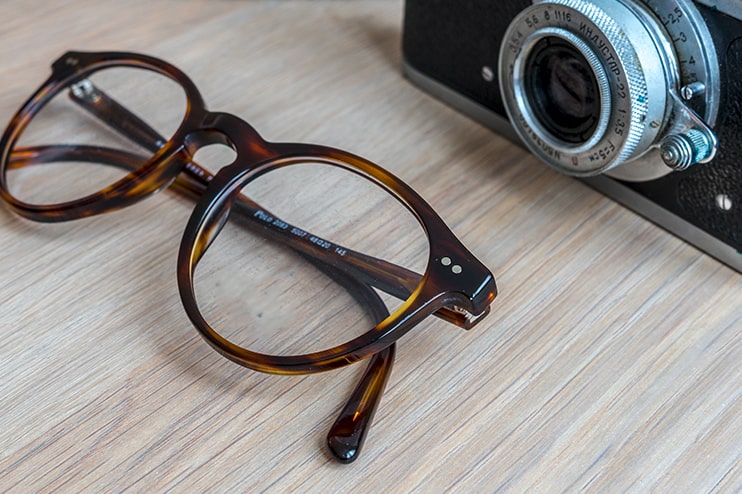 A pair of glasses lying next to a camera