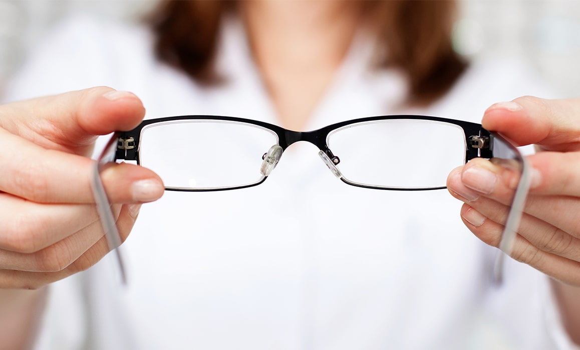 A woman holding up a pair of glasses