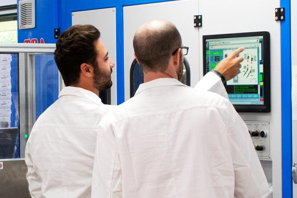 Two opticians in white coats looking at a screen in a lab