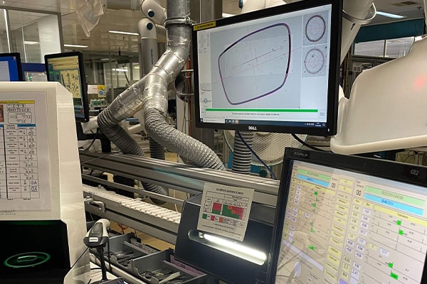 Two computer screens in a laboratory showing a diagram of a glasses lens and a form with a lot of different fields to fill out