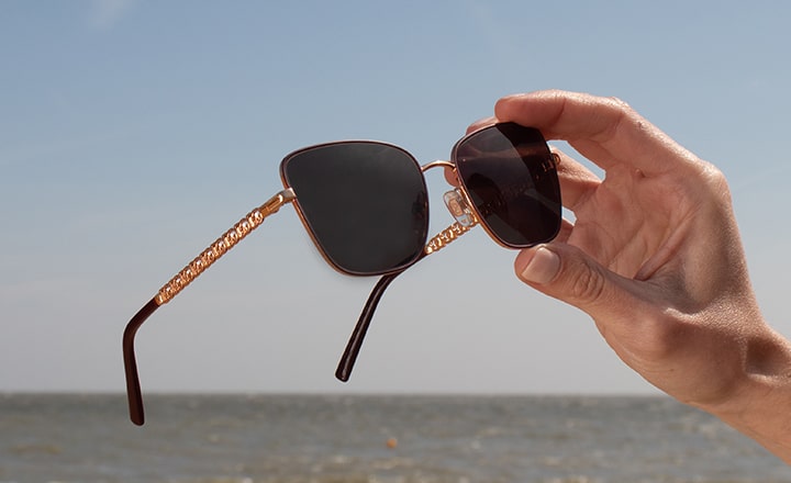A pair of sunglasses being held up to the sun