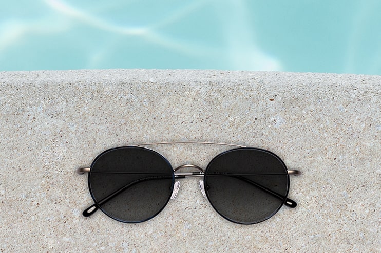 A pair of sunglasses lying by the side of a swimming pool